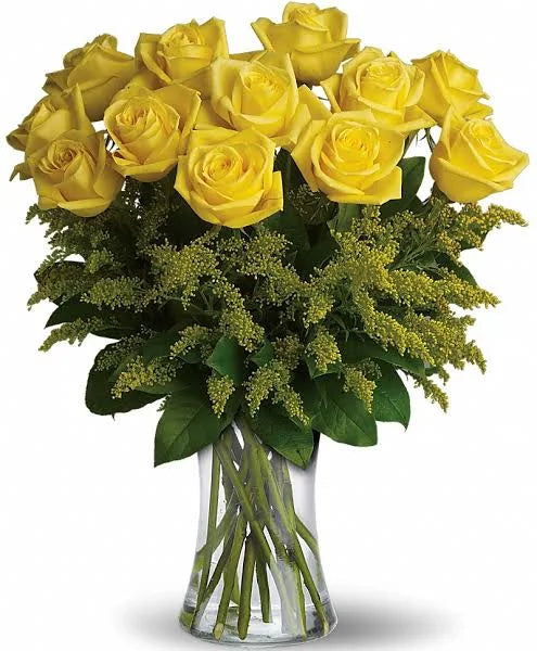 Dozen yellow roses in the vase, complimented by seasonal greenery